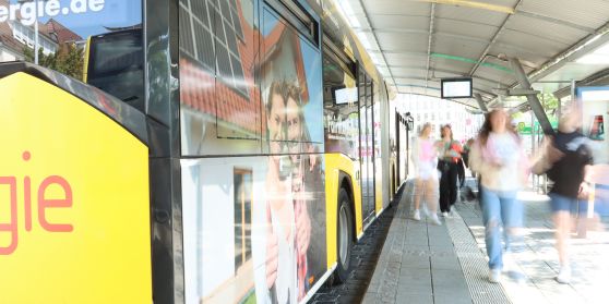 An einem wartenden Bus laufen Menschen vorbei.